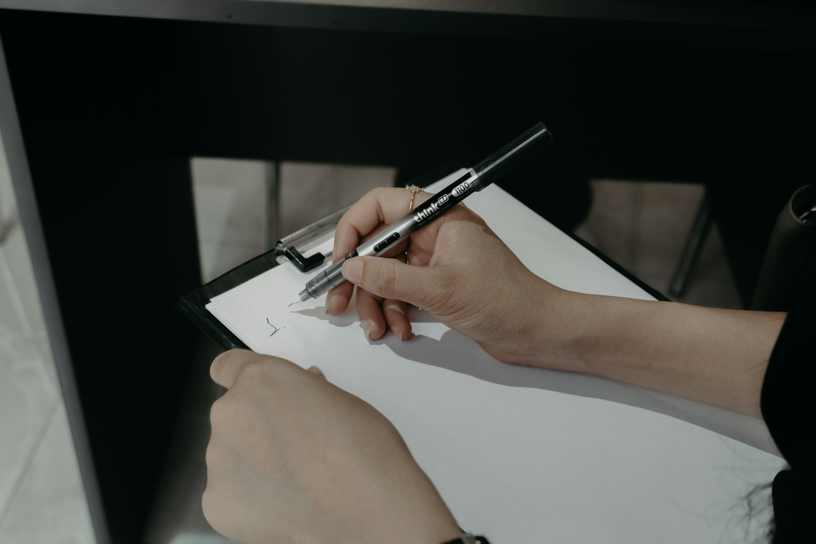 A hand holding a pen rests on a printed work-order document